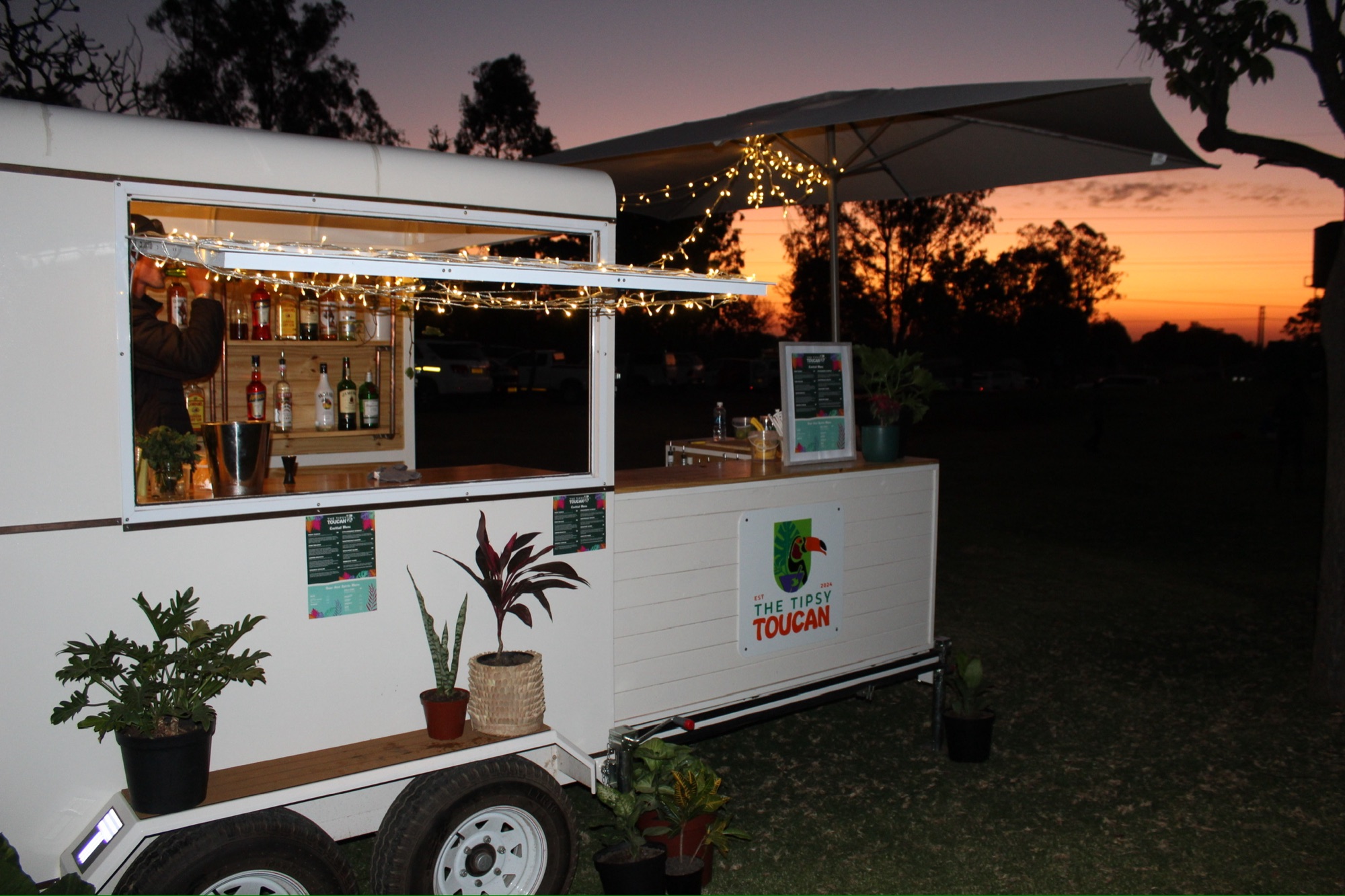 The Tipsy Toucan mobile bar lit up at sunset